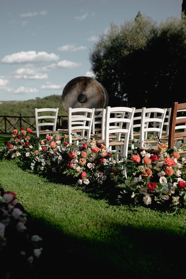 Outdoor wedding ceremony setup with white chairs and floral arrangements at Tenuta La Campana