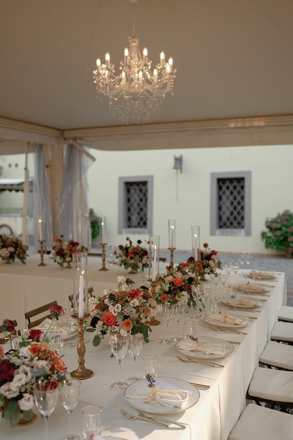 Wedding reception table decorated with flowers and candles beneath a marquee